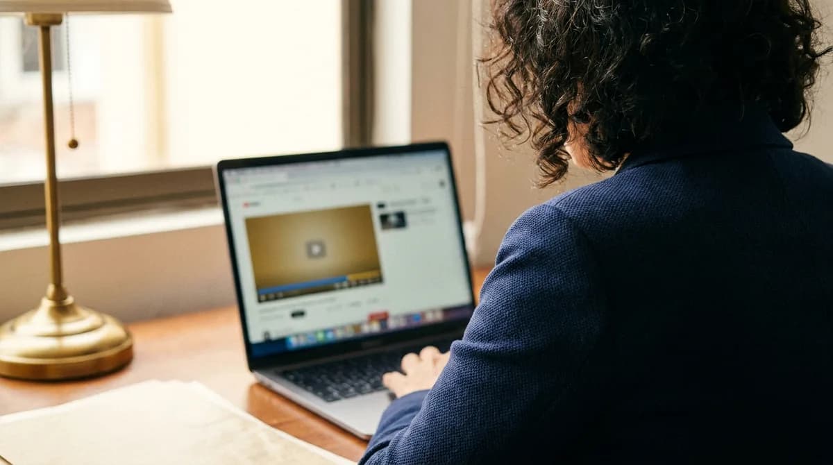 Colaborador toma un curso corporativo en línea desde su laptop en el escritorio.